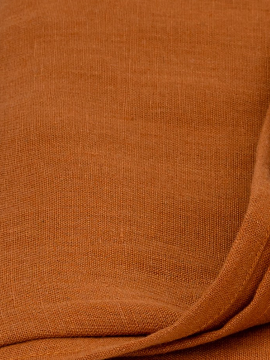 Close-up of cinnamon brown textured fabric with visible weave and a folded edge