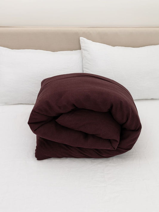 100% flax linen Elderberry Purple duvet cover rolled on bed – OEKO-TEX Standard 100, cozy & compact