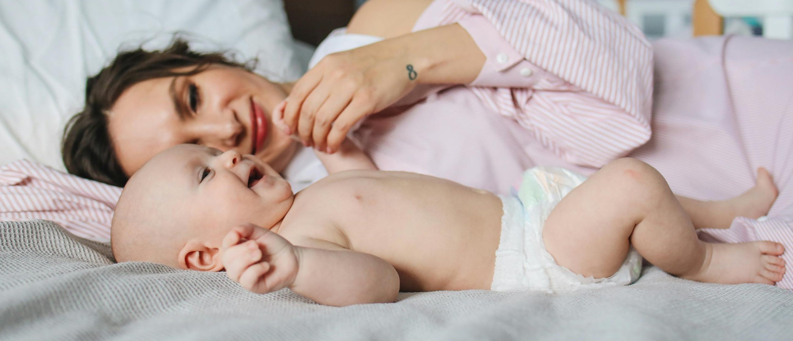 Woman lying on a bed with a baby, flax linen bedding for baby.